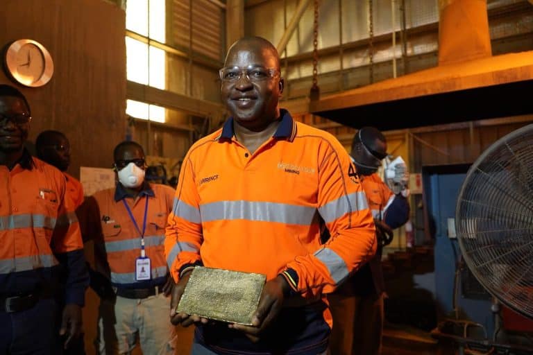 Endeavour Mining VP of Operations Lawrence Manjengwa smiling while holding a freshly poured gold bar at the Sabodala-Massawa BIOX facility in Senegal.