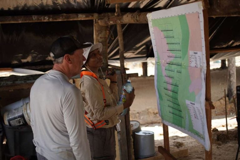 Greenheart Gold exploration team reviewing a geological map inside a covered shelter.