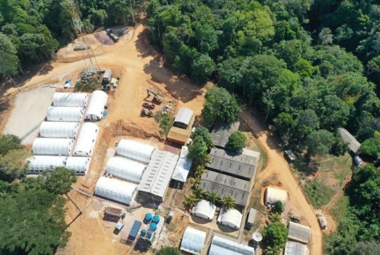 Aerial view of the G Mining Ventures exploration camp facility and temporary structures surrounded by dense tropical forest.