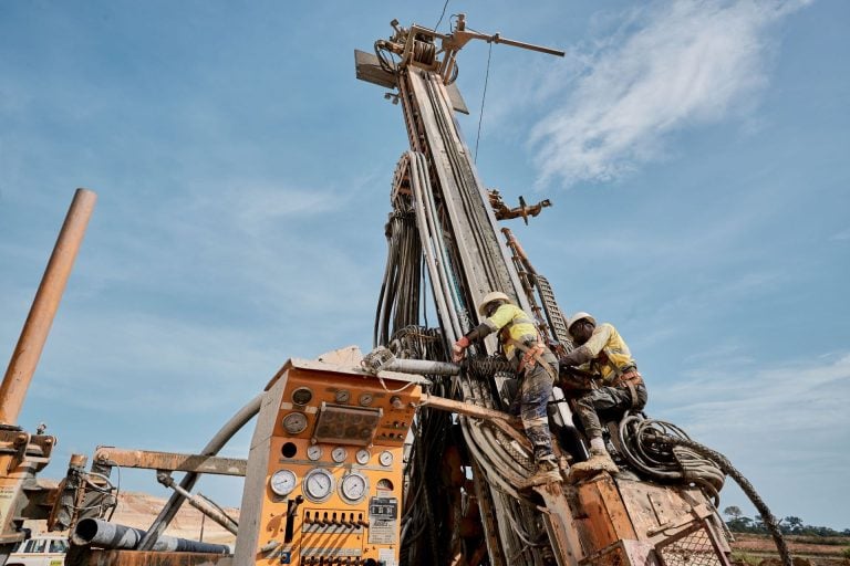 Mining workers operating a large drill rig at an Endeavour Mining gold exploration site in West Africa.