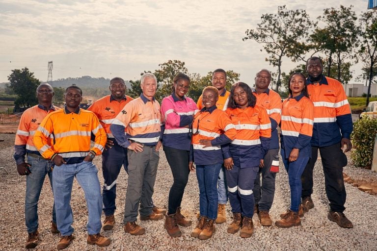 Group portrait of local employees wearing high-visibility work shirts at Endeavour Mining's Lafigué gold mine site in Côte d'Ivoire.