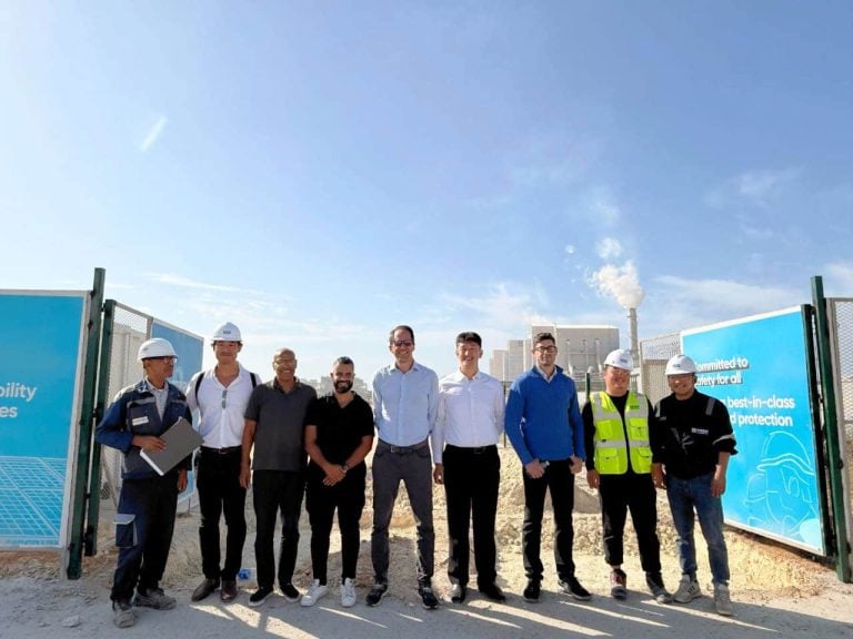 Group portrait of the Falcon Energy Materials team standing outdoors at the entrance of a facility construction site in Morocco.
