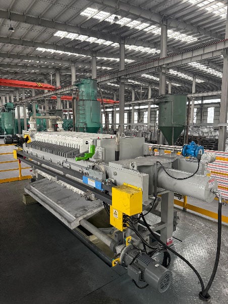Interior of a Falcon Energy Materials graphite processing facility showing industrial machinery and overhead cranes.