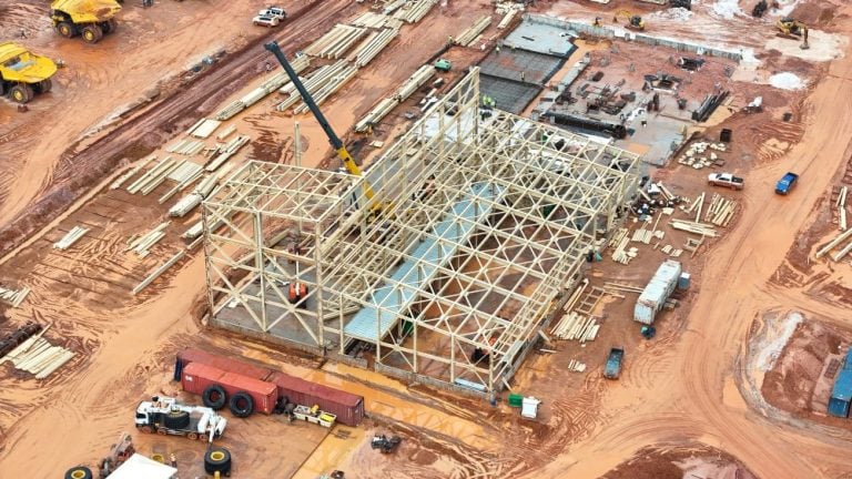 Aerial view of structural steel framework construction for an Endeavour Mining gold mine processing facility with cranes and heavy equipment.